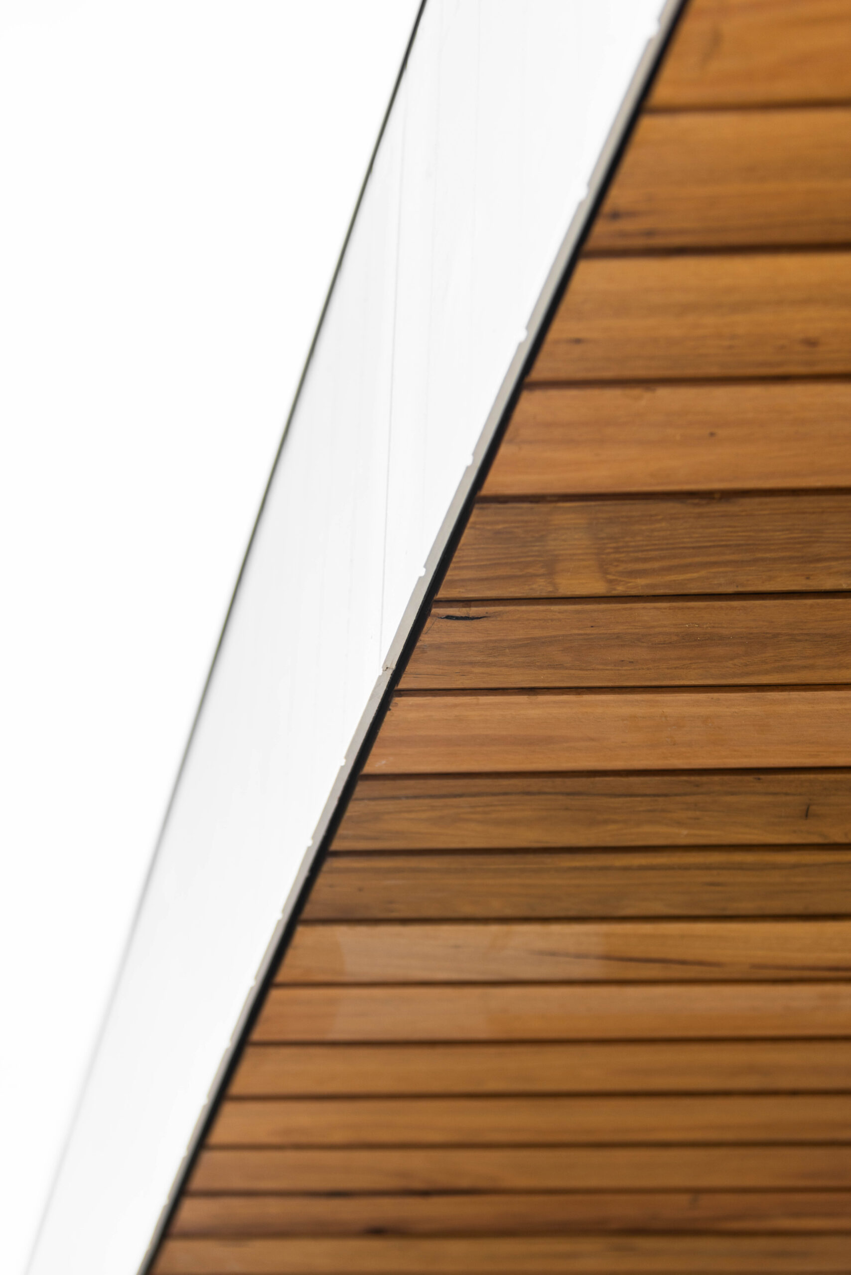 Timber cladding covering a roof and meeting the wall flush with VJ panelling.