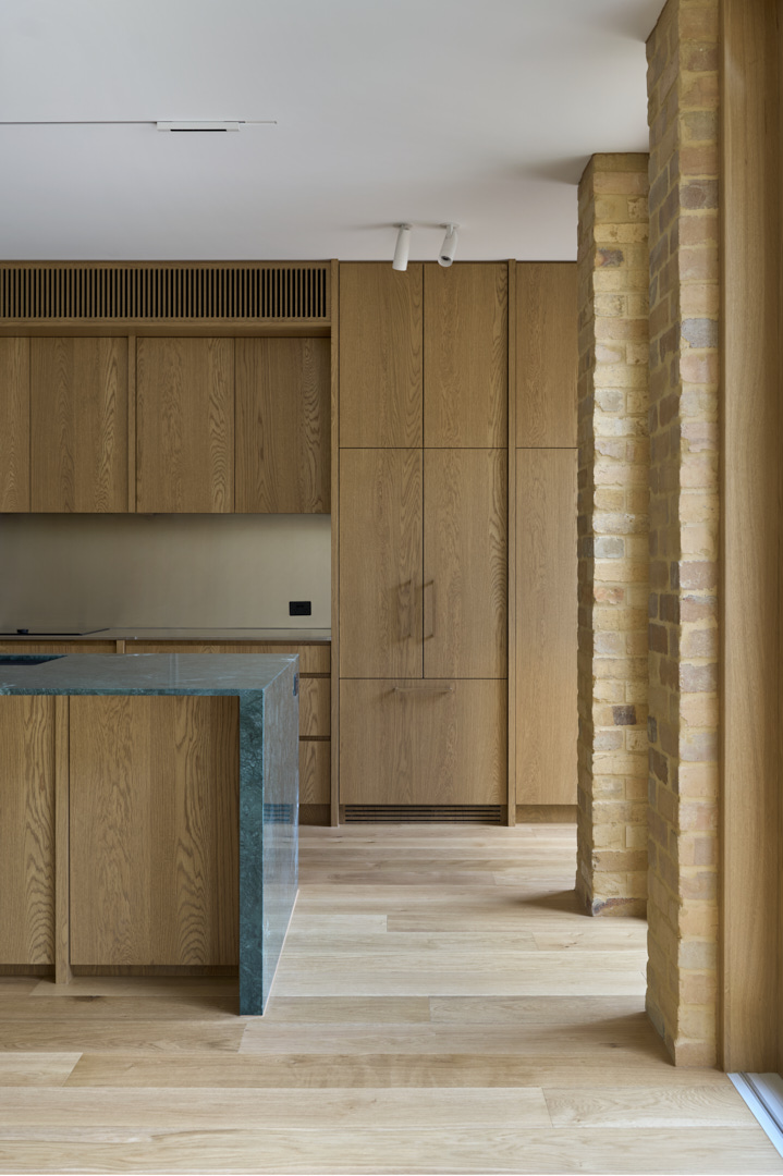 Kitchen and living space in a Fitzroy home featuring timber cabinetry, brick columns and integrated storage built by HONE.