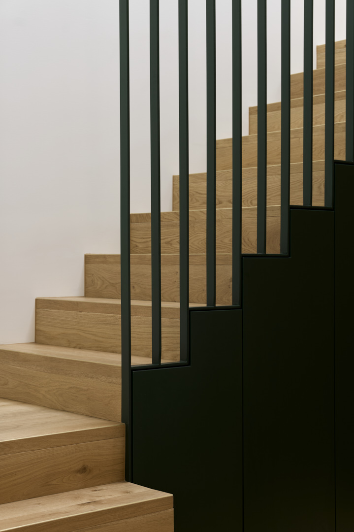 Timber stair with black steel balustrade inside a Fitzroy home, demonstrating precise carpentry and clean detailing.