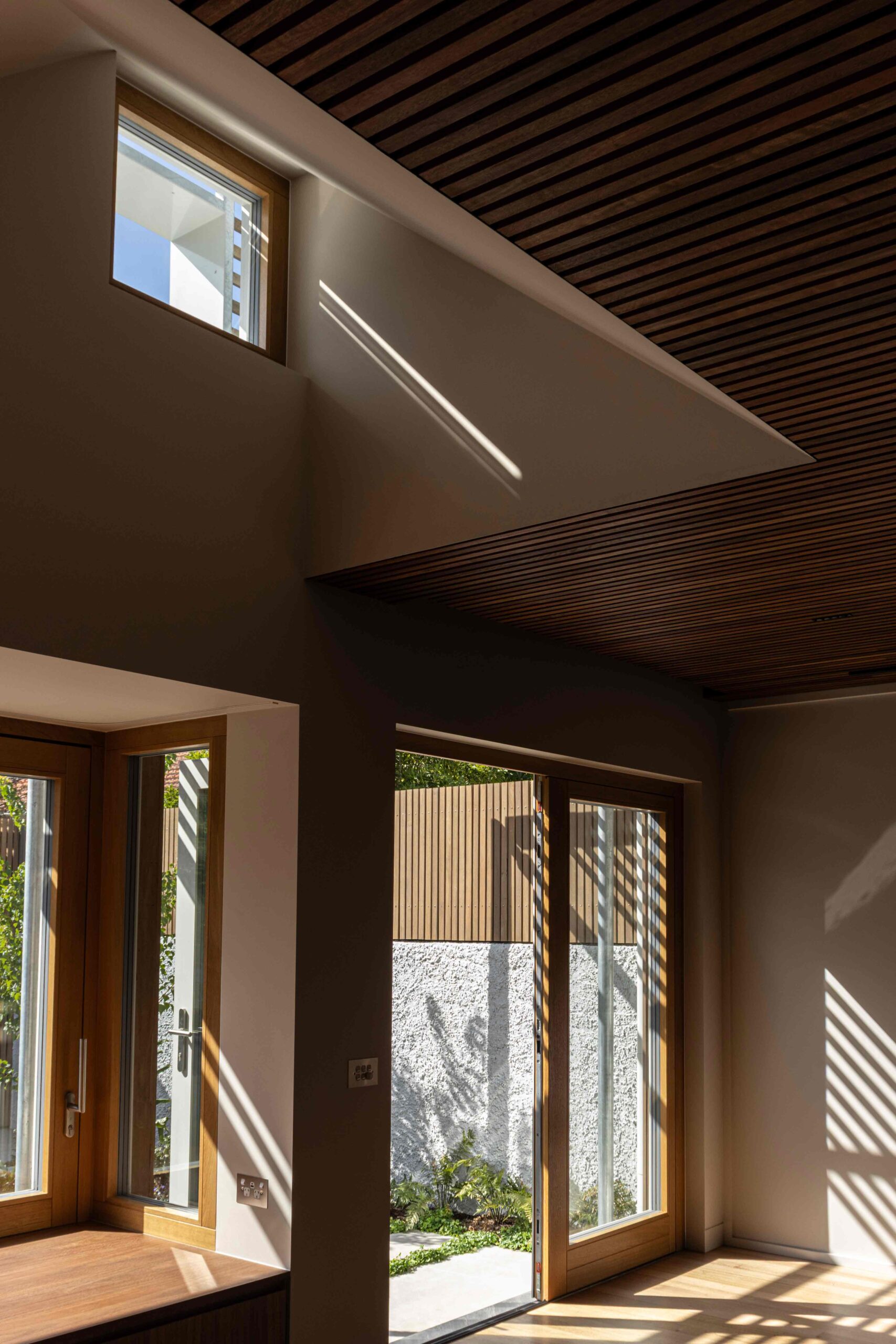 Timber-lined living space in Hampton high-performance retrofit with garden connection and natural daylight